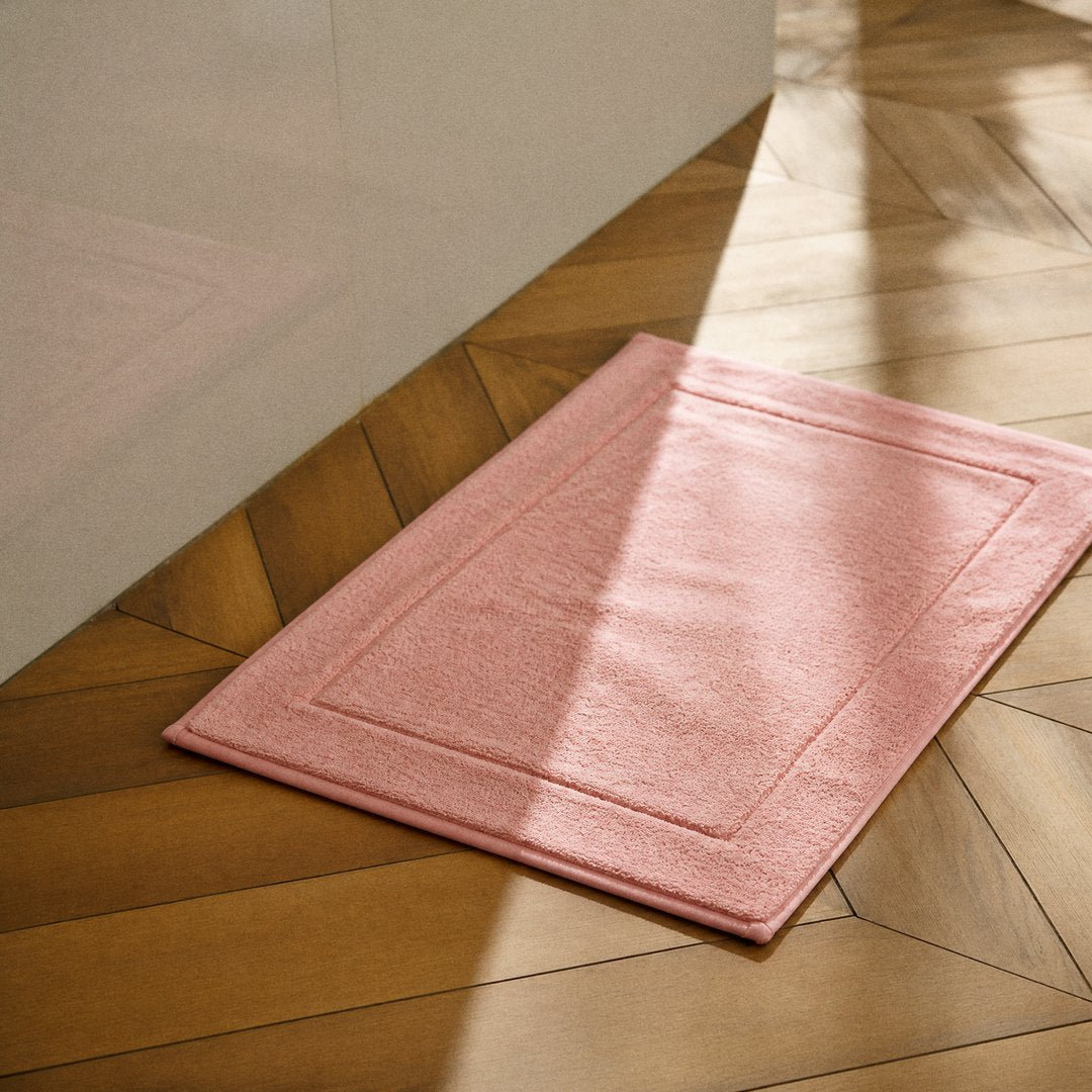 Cotton Bath Mat on the bathroom floor (Coral Pink)